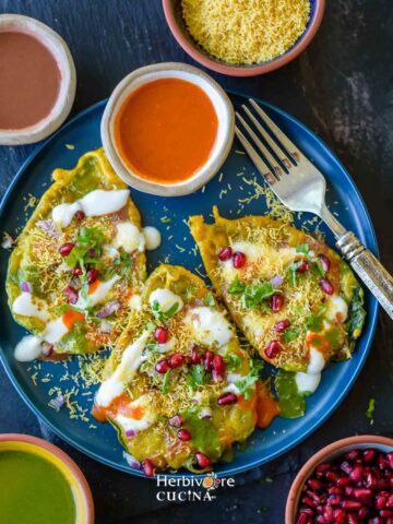 Paan Chaat served in a plate nad topped with chutneys, vegetables and toppings.