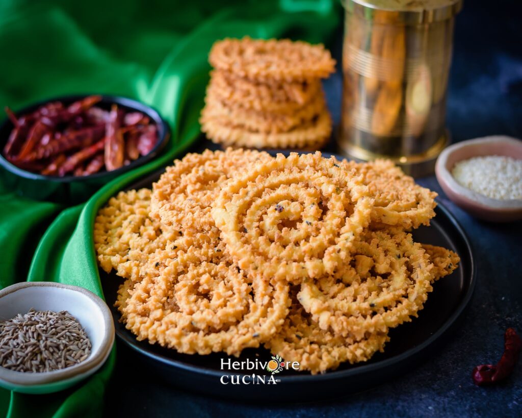 A plate with chakli with more chakli on the side. 