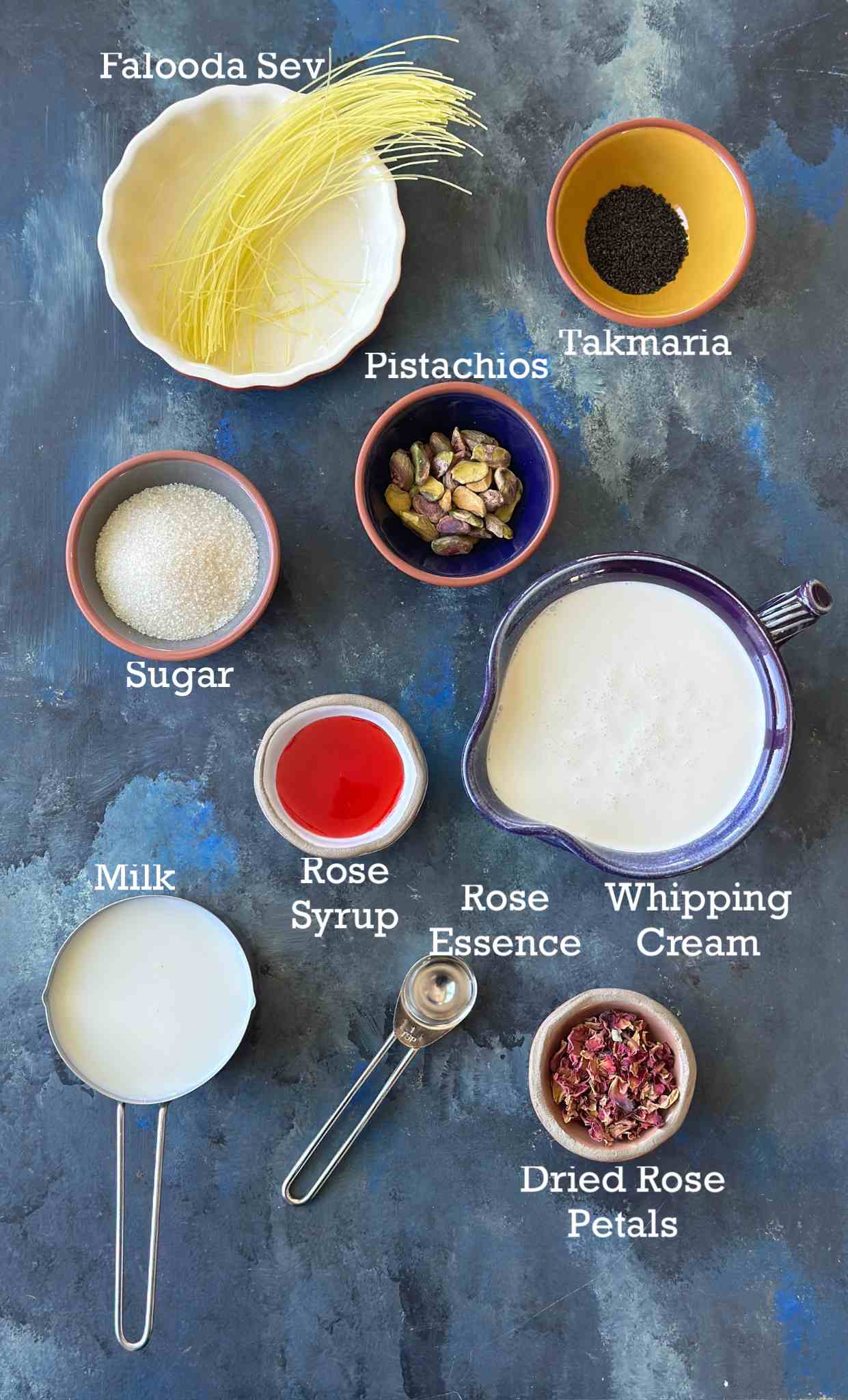 Ingredients of rose falooda ice cream in small bowls on a dark background. 