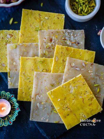 Ice Halva sheets placed on top of one another with diya and pistachios in the background.