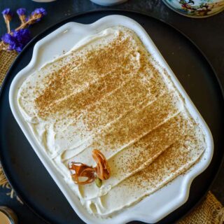 A tray filled with masala chai tiramisu topped with chai masala and served with some spices on the side.