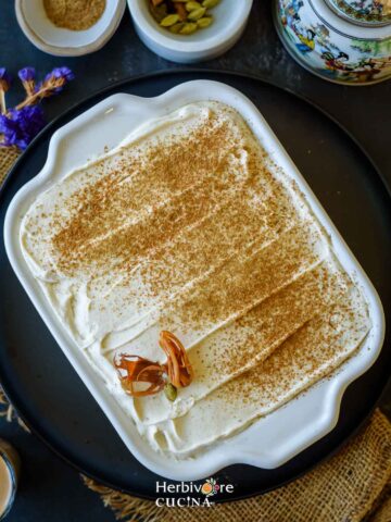 A tray filled with masala chai tiramisu topped with chai masala and served with some spices on the side.