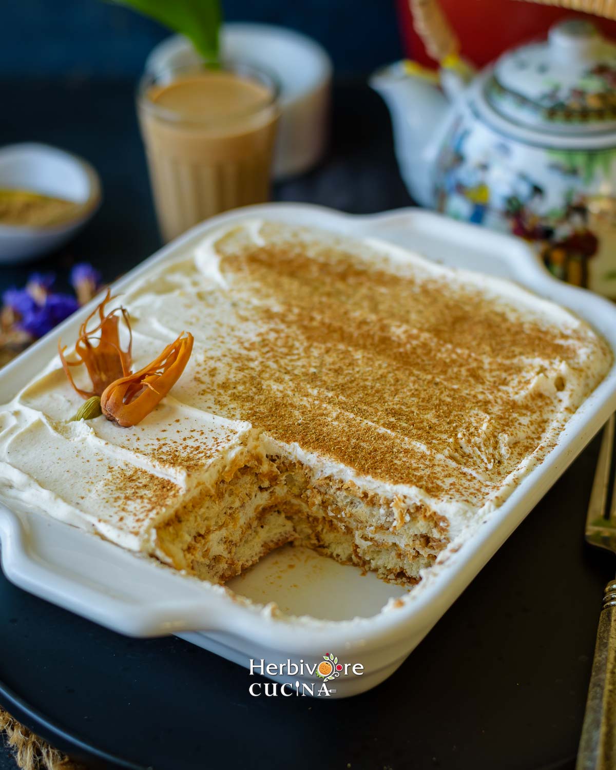 The layers of masala chai tiramisu in a tray topped with chai masala. 