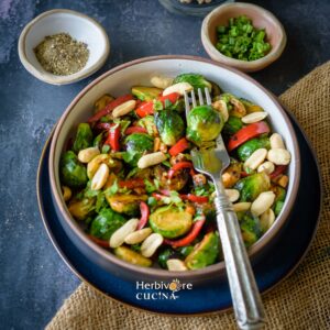 A bowl filled with stir fried Brussels Sprouts with peppers and a fork on the side.