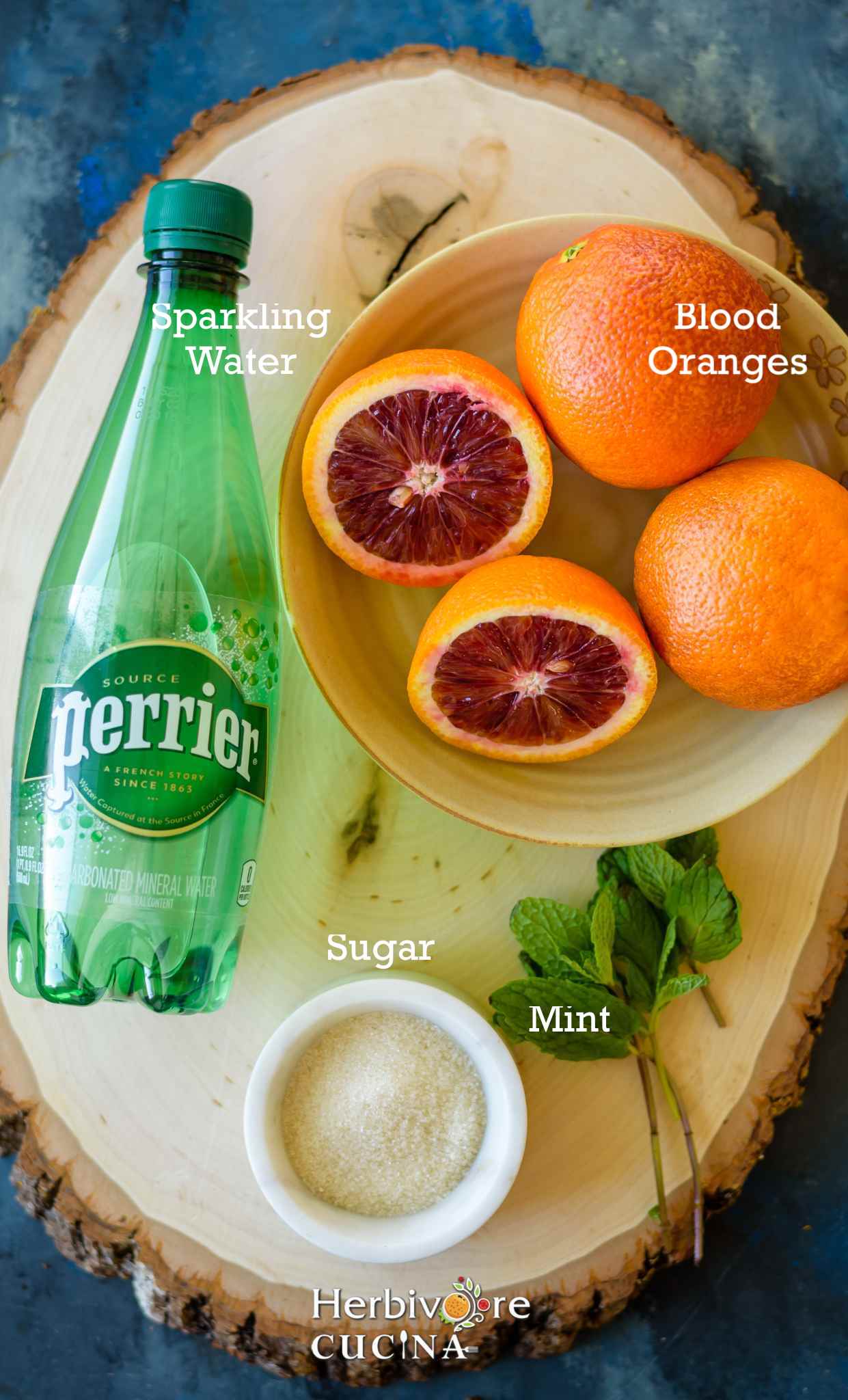 Ingredients to make blood orange lemonade in small bowls on a wooden plank. 