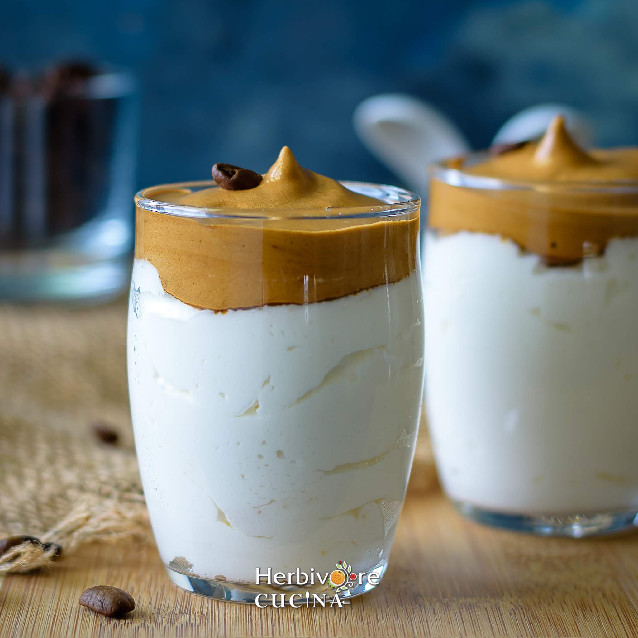 Jars of dalgona coffee mousse topped with whipped coffee and served with coffee bean on top. 