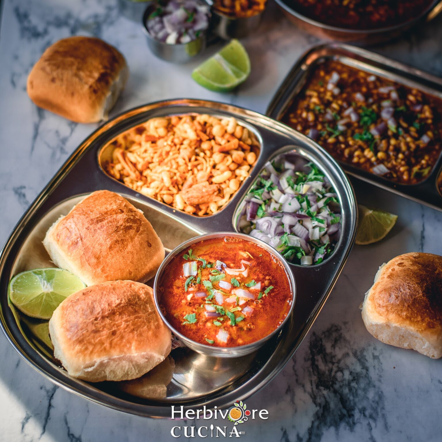 Matki Misal and pav in a steel plate with mixed farsan and onions to serve as a breakfast platter. 