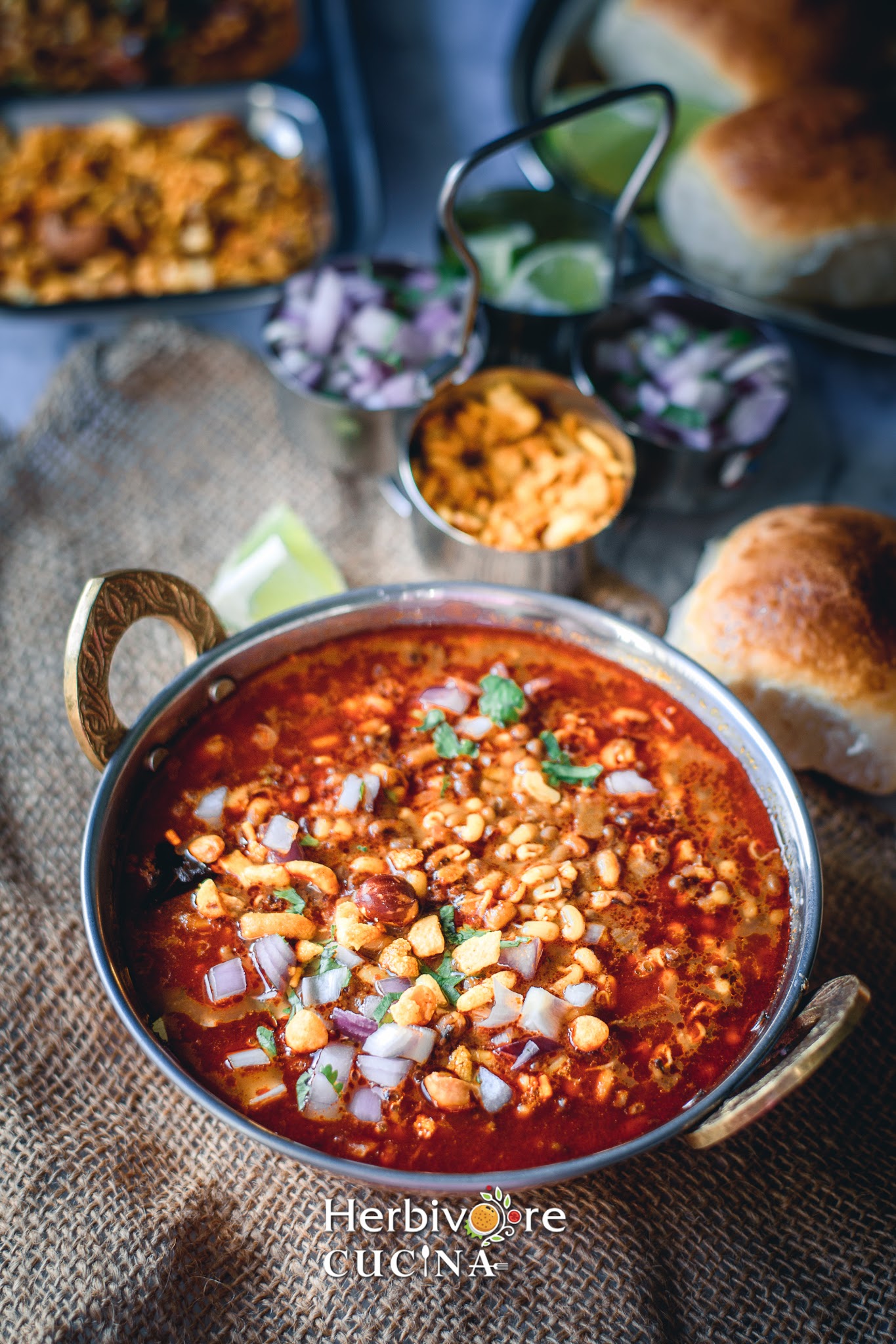 Matki misal in a bowl with onions and cilantro toppings with some pav on the side. 