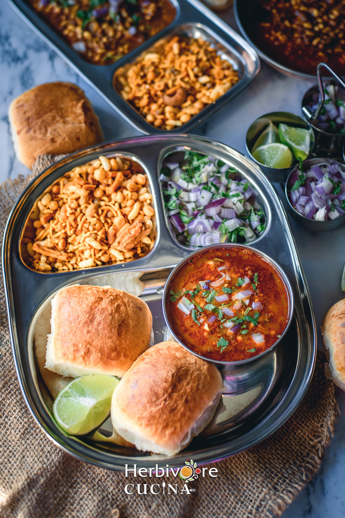 A plate with misal and pav with onions with farsan in a steel plate. 