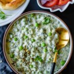 Methi Matar Malai in a bowl with salad and naan on the side in bowls.