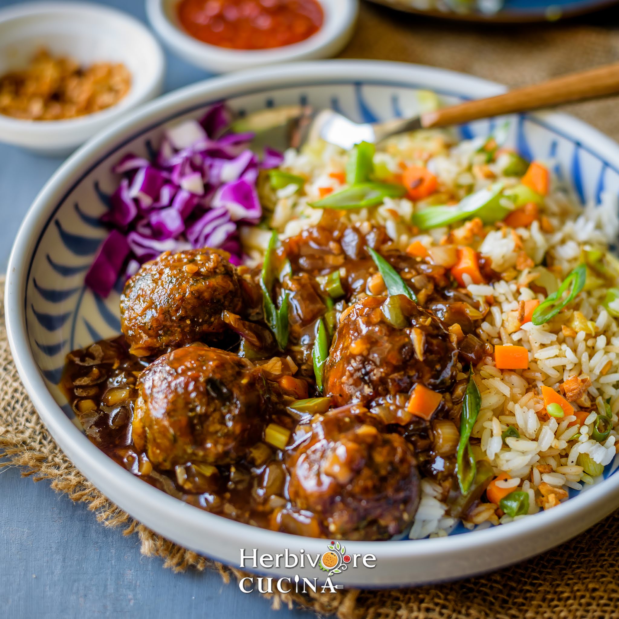 Vegetable Manchurian in gravy with fried rice and cabbage salad in a plate with some hot sauce on the side. 