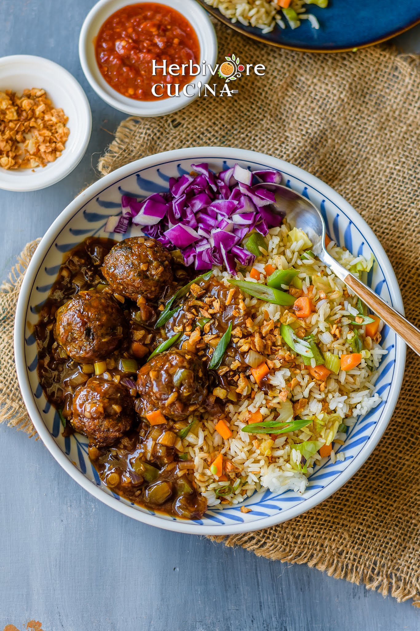 A plate with non-fried manchurian with fried rice and cabbage salad with sauce on the side. 
