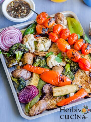 Balsamic Grilled vegetables in a tray with more sauce and juice on the side.