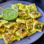 A grey platter with dudhi dhokla and cilantro chutney on the side.